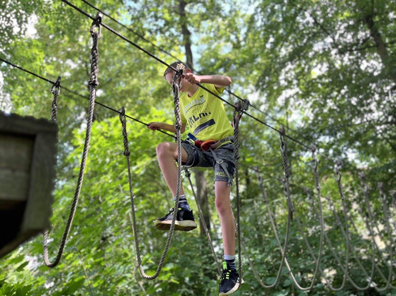 Jugendlicher auf dem Seil-Hindernisparcours im Kletterwald